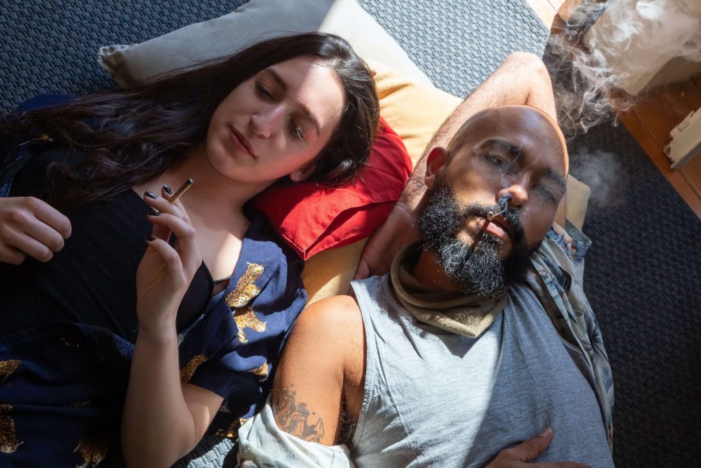couple laying on the bed smoking weed to cure hangover